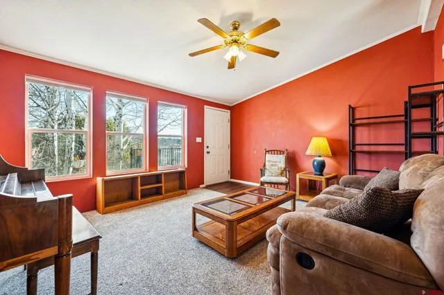 a living room with furniture a ceiling fan and a large window