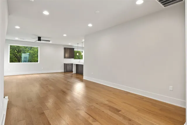 an empty room with wooden floor a fireplace and windows