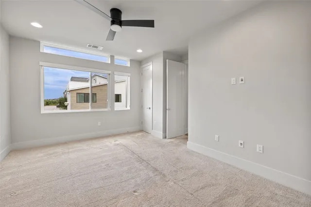 an empty room with windows and chandelier fan