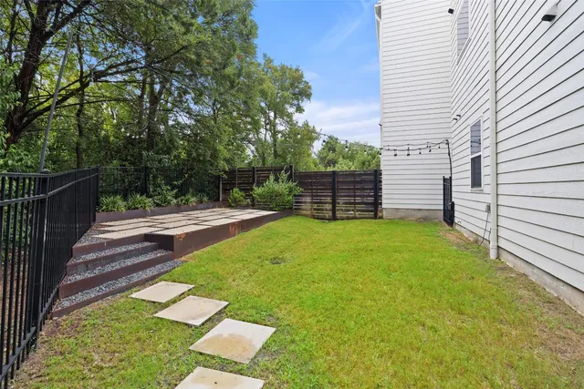 a backyard of a house with plants and large tree
