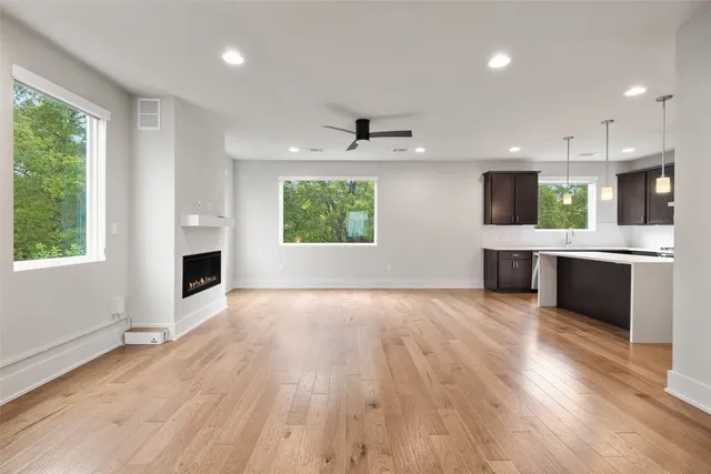 an empty room with a kitchen and wooden floor