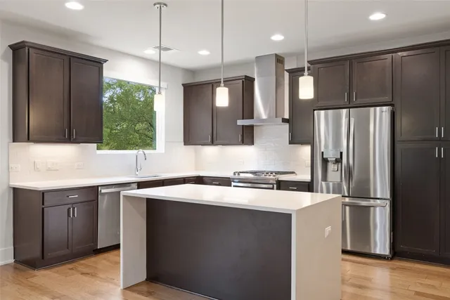 a kitchen with a sink a center island cabinets and stainless steel appliances
