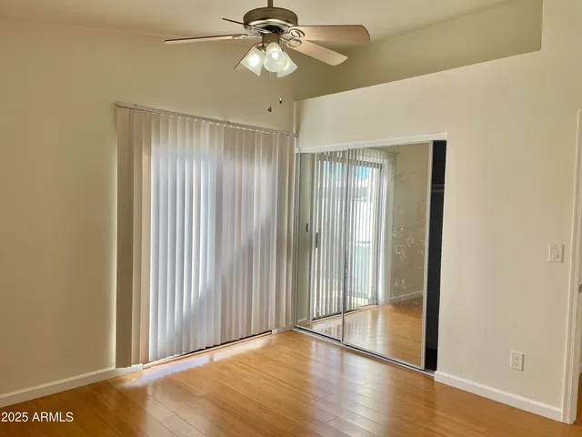an empty room with wooden floor fan and windows