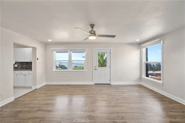 a view of an empty room with a window and wooden floor