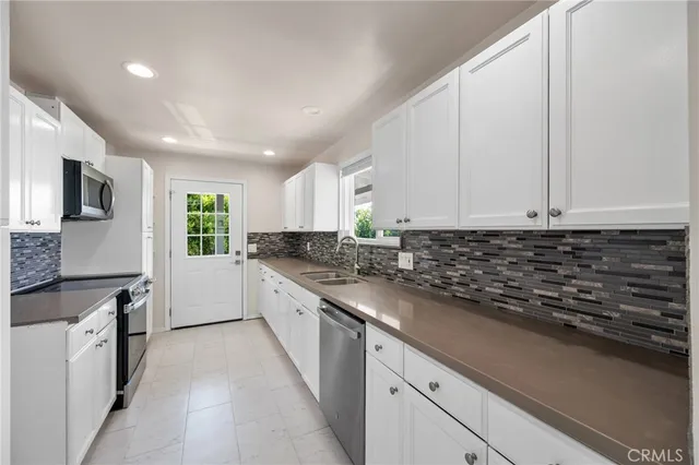 a kitchen with granite countertop white cabinets and stainless steel appliances