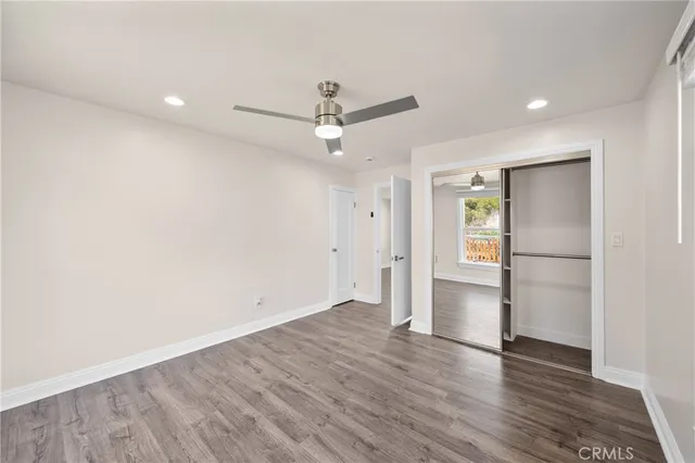 an empty room with wooden floor and ceiling fan