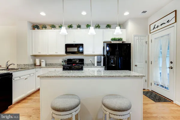 a kitchen with stainless steel appliances kitchen island granite countertop a refrigerator and a stove top oven