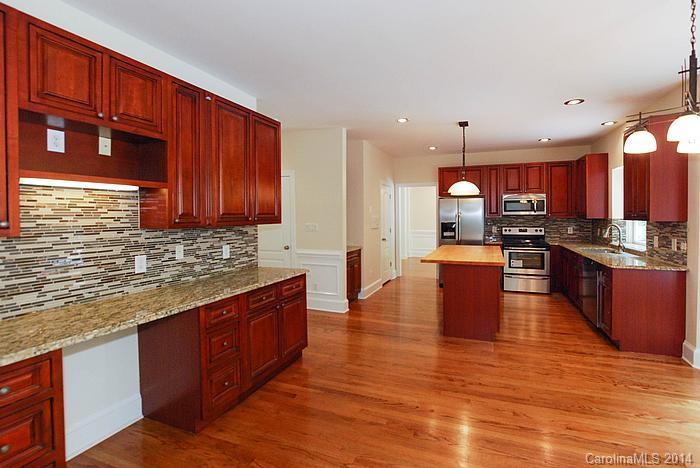 7131 Forest Ridge Road Weddington, NC 28104 - Photo 9 of 23 a kitchen with stainless steel appliances granite countertop wooden cabinets a stove top oven a sink and dishwasher a dining table with wooden floor