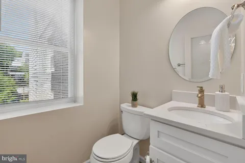 a bathroom with a toilet a sink a mirror and a window