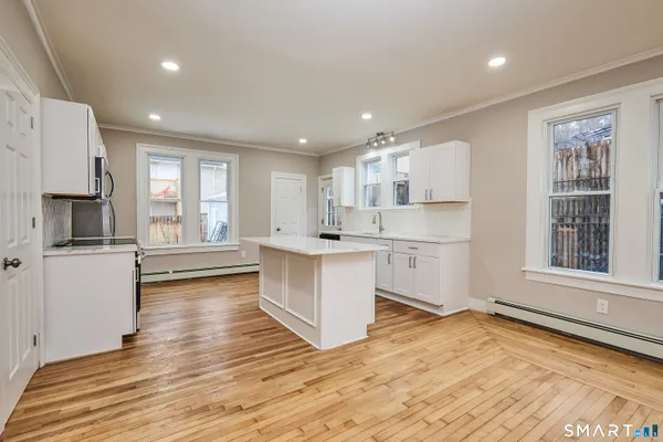a large kitchen with stainless steel appliances granite countertop a stove a sink dishwasher and a refrigerator with wooden floor