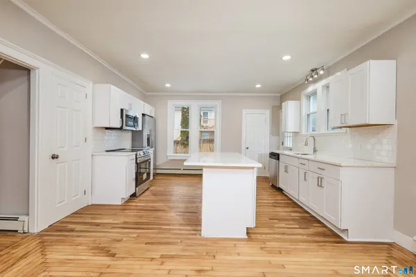 a large kitchen with a sink stainless steel appliances and cabinets