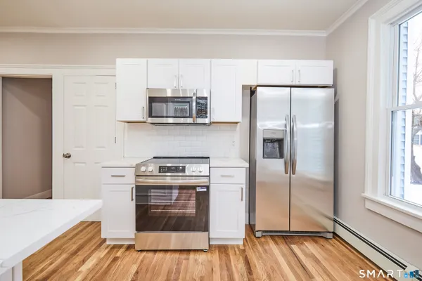 a kitchen with granite countertop white cabinets and white appliances