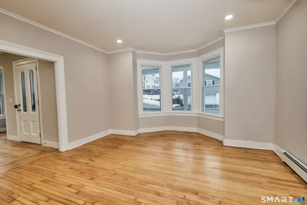 a view of an empty room with a window and wooden floor