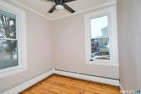 a view of an empty room with wooden floor and a window