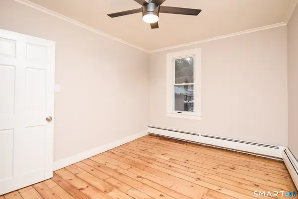 a view of empty room with wooden floor and fan