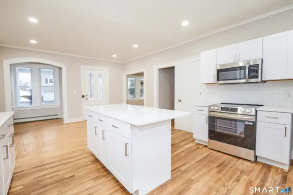 a kitchen with kitchen island white cabinets and refrigerator