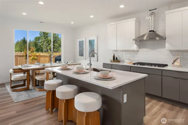 a kitchen with stainless steel appliances granite countertop a kitchen island hardwood floor sink stove dining table and chairs