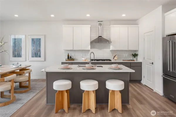 a kitchen with stainless steel appliances granite countertop a sink a stove a refrigerator and chairs