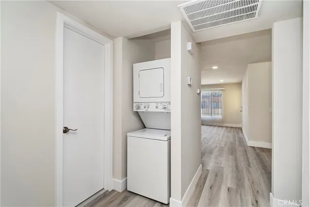 a view of a hallway with wooden floor and washer and dryer