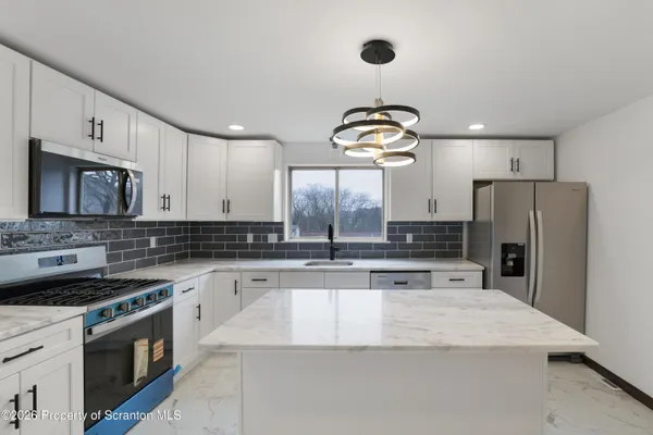 a kitchen with stainless steel appliances granite countertop a sink a stove and refrigerator