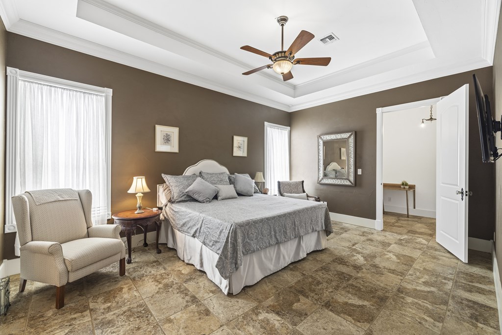 150 St Andrews Loop Kerrville, TX 78028 - Photo 15 of 27 a spacious bedroom with a bed a couch and a chandelier