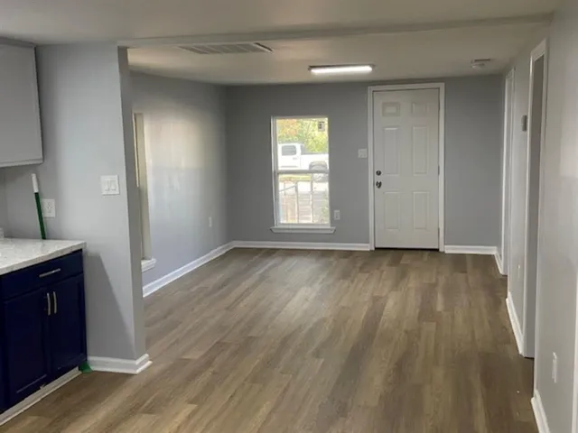 an empty room with wooden floor and windows