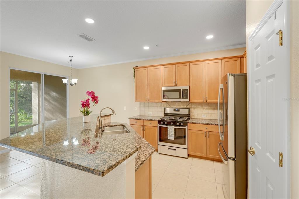 839 Assembly Court Reunion, FL 34747 - Photo 3 of 31 a kitchen with stainless steel appliances granite countertop a sink and refrigerator