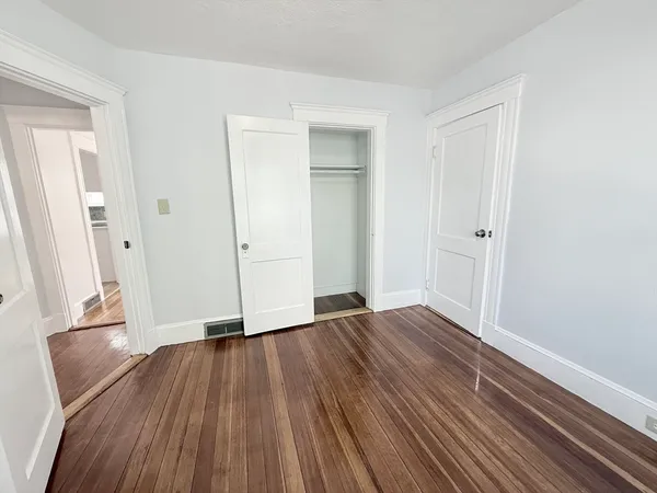 an empty room with wooden floor and a bathroom