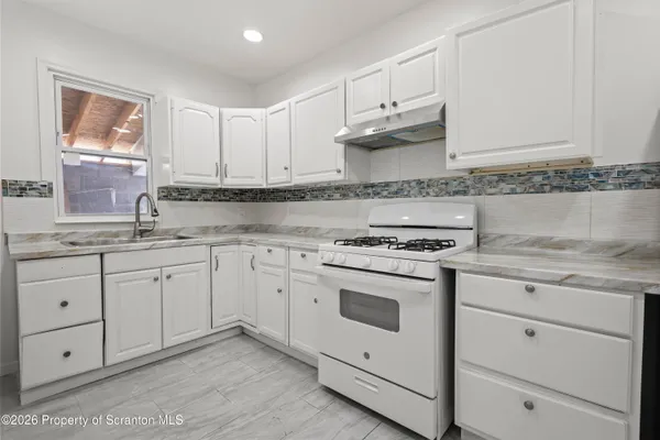 a kitchen with granite countertop white cabinets and white appliances