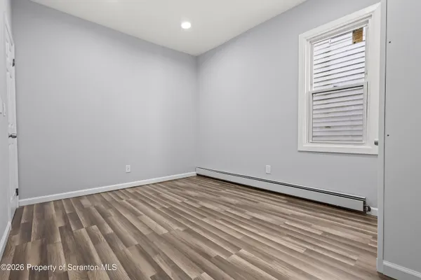 a view of an empty room with wooden floor and a window