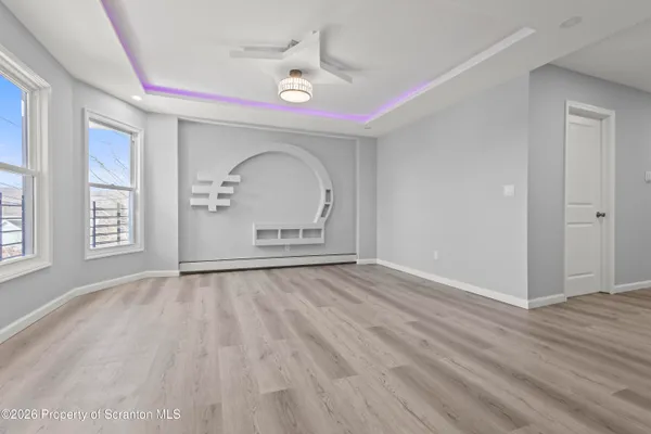 a view of empty room with wooden floor and fan