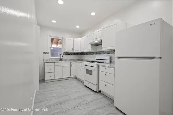 a kitchen with cabinets appliances a sink and a window
