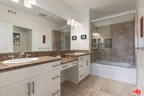 a bathroom with a granite countertop sink mirror and a bathtub