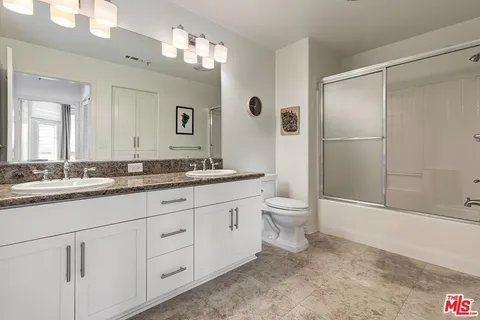 a bathroom with a granite countertop sink toilet and shower