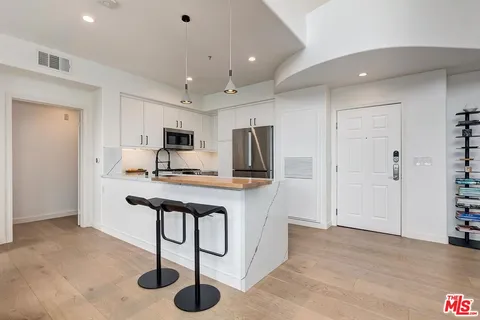a kitchen with stainless steel appliances granite countertop a refrigerator and a stove top oven