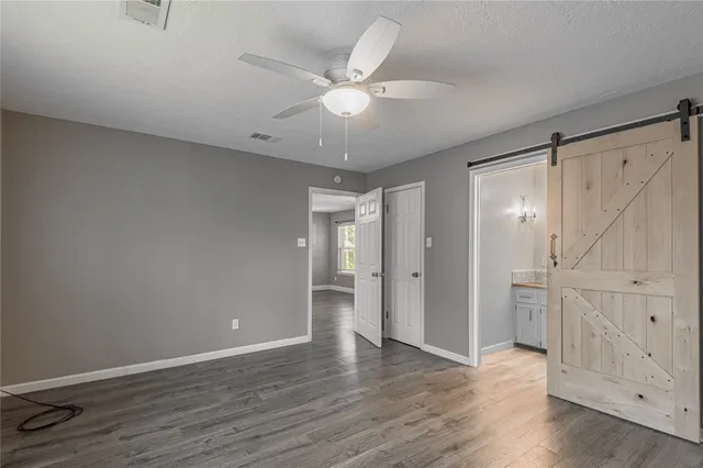 an empty room with wooden floor and a ceiling fan