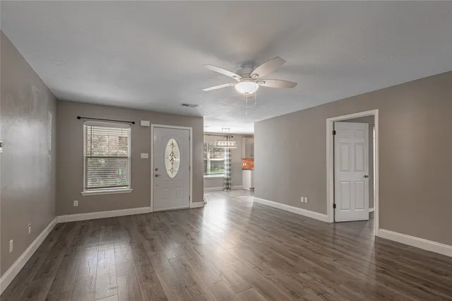 a view of an empty room with a window and wooden floor