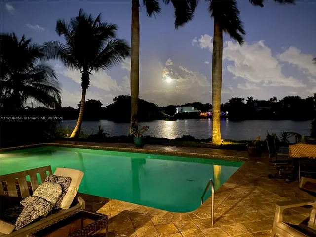 a view of a lake with a yard and palm trees