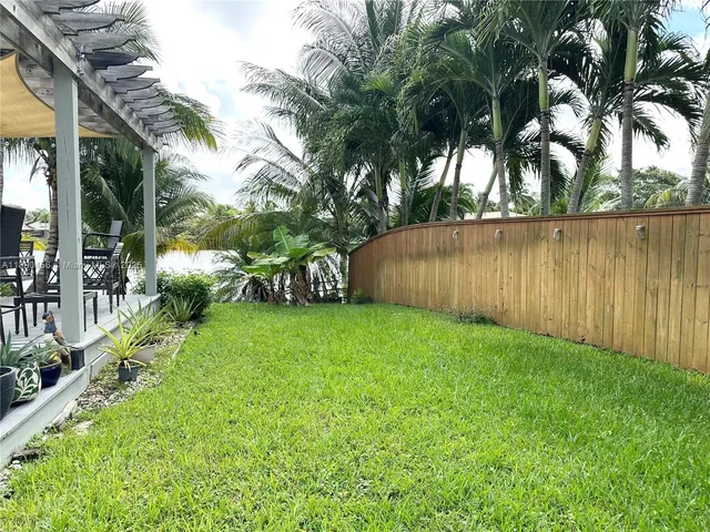 a view of a backyard with potted plants and large tree