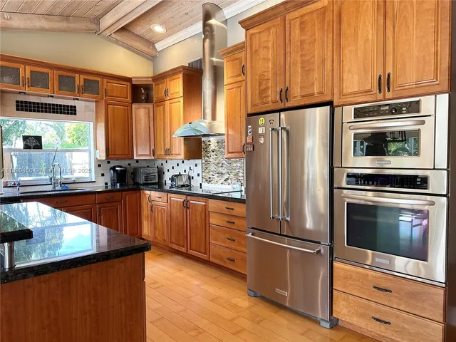 a kitchen with stainless steel appliances granite countertop a refrigerator a stove and a sink