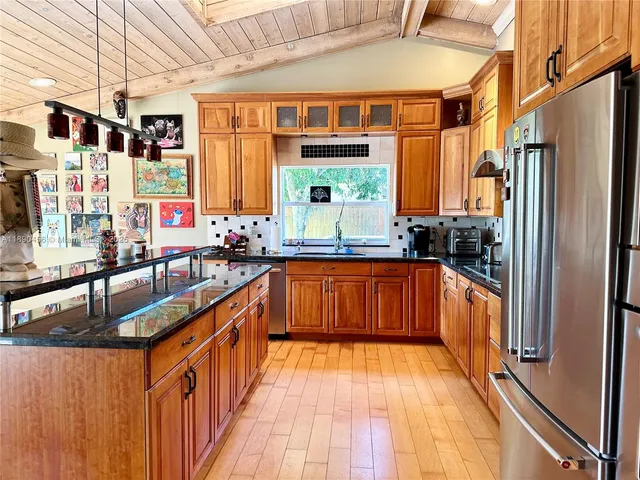 a kitchen with stainless steel appliances granite countertop a stove a sink and a refrigerator