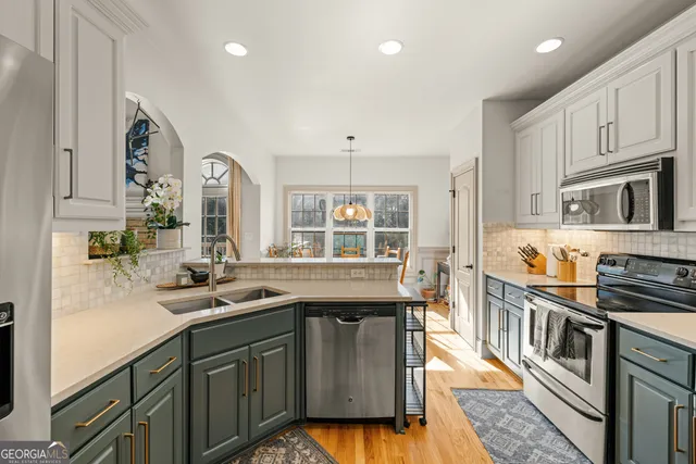 a kitchen with stainless steel appliances granite countertop a stove a sink dishwasher a dining table and chairs with wooden floor