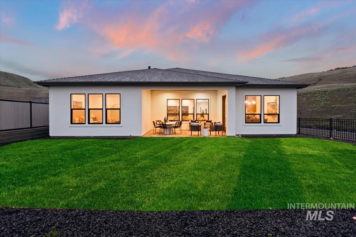 7615 Brown Way Eagle, ID 83714 - Photo 39 of 43 Rear exterior featuring a covered patio, a manicured lawn, and a dark gravel border