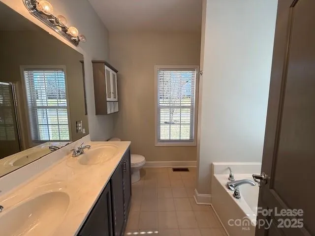 a en suite bathroom with a tub sink and mirror