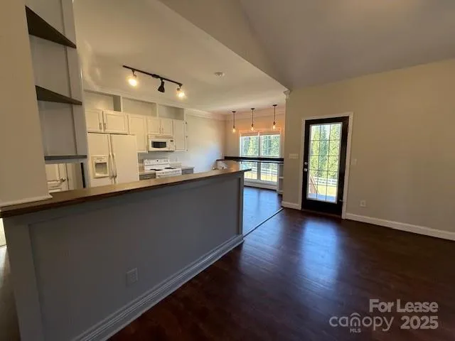 a kitchen with stainless steel appliances granite countertop a refrigerator a sink dishwasher a stove and a dining table with wooden floor