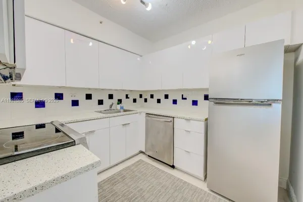 a white kitchen with stainless steel appliances a sink and a refrigerator