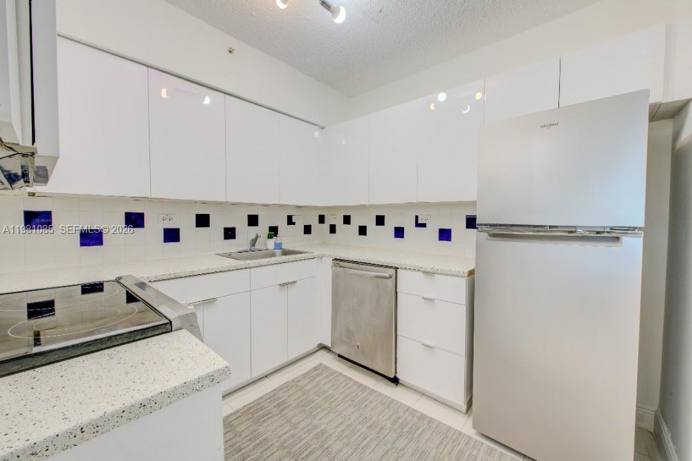 1500 Bay Road, Unit 528S Miami Beach, FL 33139 - Photo 11 of 11 a white kitchen with stainless steel appliances a sink and a refrigerator