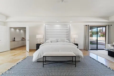 a spacious bedroom with a bed a couch and large window