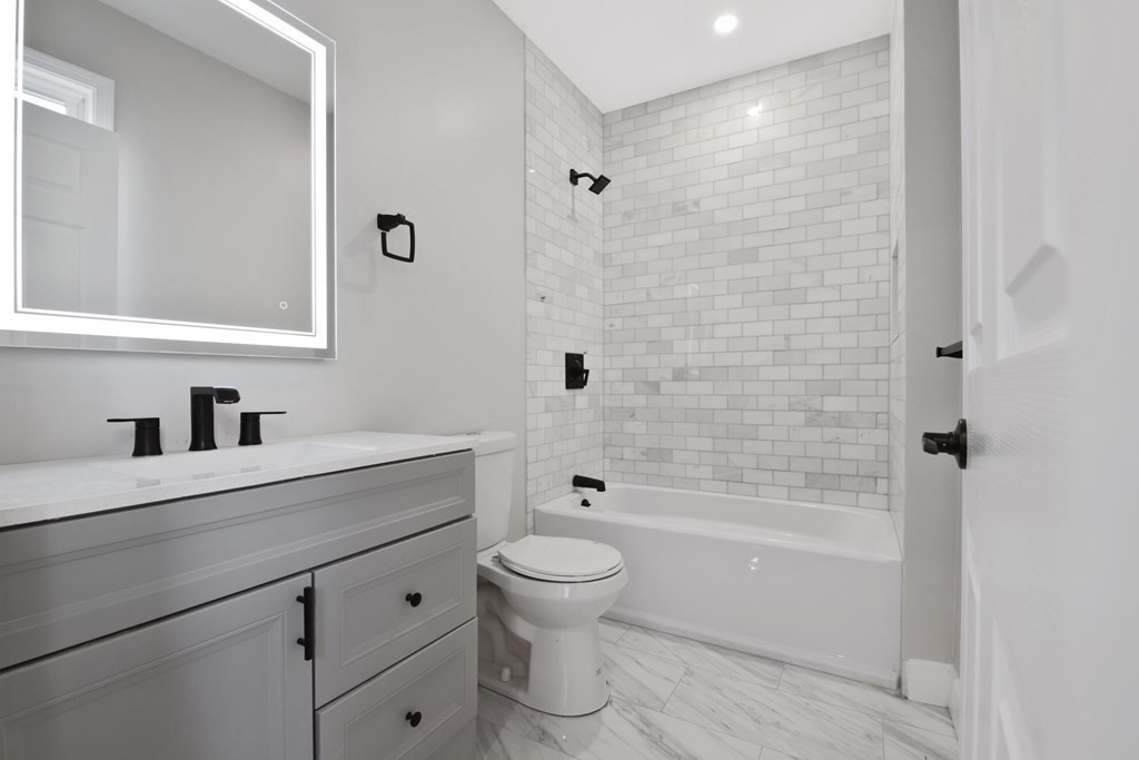 41 School Street, Unit 1 Boston, MA 02124 - Photo 13 of 25 a bathroom with a bathtub shower sink mirror and toilet