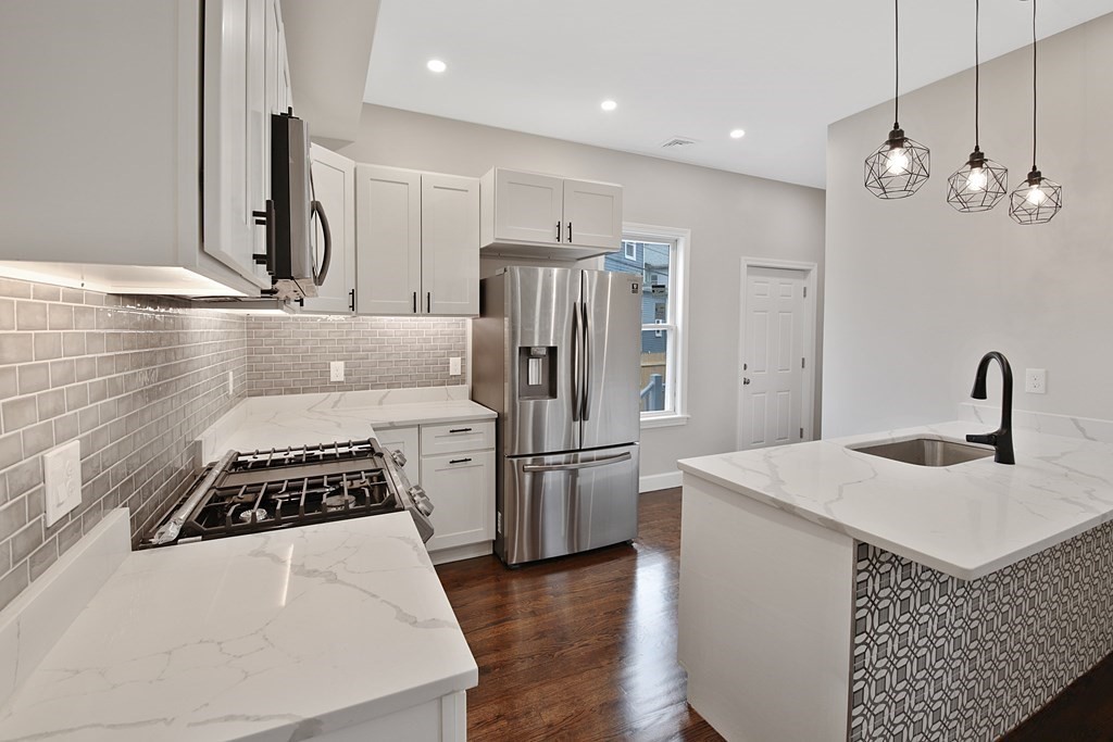 41 School Street, Unit 1 Boston, MA 02124 - Photo 15 of 25 a kitchen with stainless steel appliances granite countertop a sink stove and refrigerator